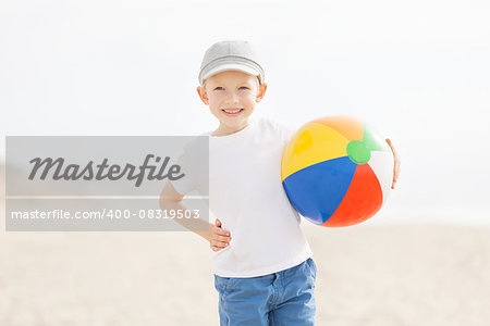 positive smiling boy holding beach ball at the beach in california