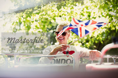 Smiling woman waving British flag on double-decker bus