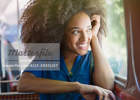 Smiling woman with afro riding bus looking out window