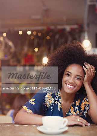 Portrait smiling woman with afro drinking coffee in cafe