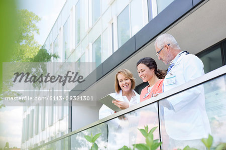 Doctors and nurse reviewing medical record on hospital balcony Doctors and nurse reviewing medical record on hospital balcony