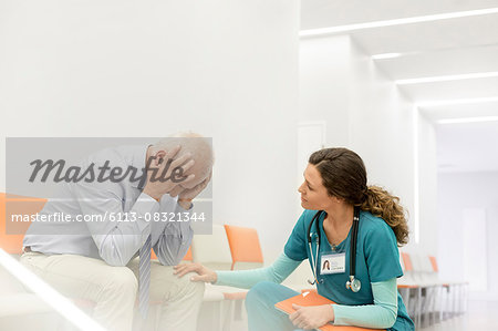 Nurse consoling upset man in clinic corridor