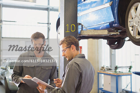 Mechanics reviewing paperwork in auto repair shop