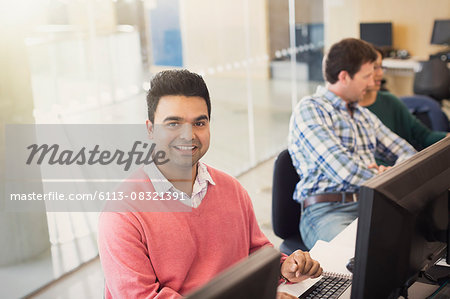 Portrait smiling adult education student at computer in classroom