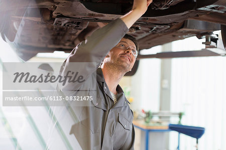 Mechanic working under car in auto repair shop