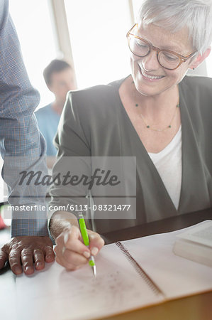Senior woman reviewing homework in adult education classroom