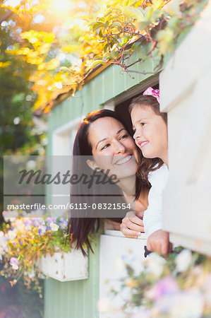 Smiling mother and daughter in playhouse window