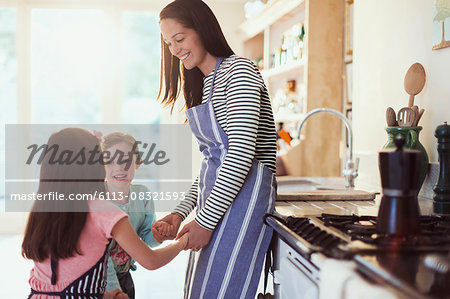 Mother and daughters holding hands in kitchen