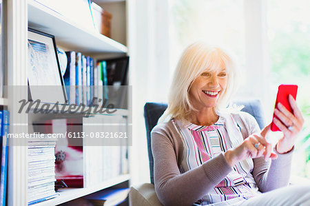 Smiling senior woman texting in living room