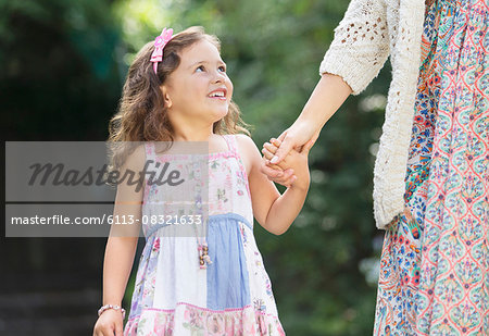 Smiling girl in dress holding mother's hand