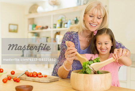 Grandmother and granddaughter tossing salad in kitchen