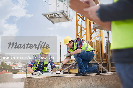 Construction workers using level tool at construction site