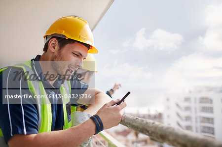 Construction worker texting at highrise construction site