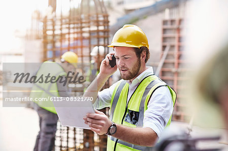 Engineer with digital tablet talking on cell phone at construction site