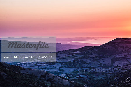 Orange sunset over ocean and rugged mountain farmland, Castelsardo, Sardinia, Italy