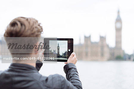 Rear view of young man photographing Big Ben on digital tablet, London, England, UK
