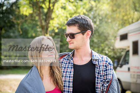 Young couple wrapped in blanket, outdoors, face to face, smiling