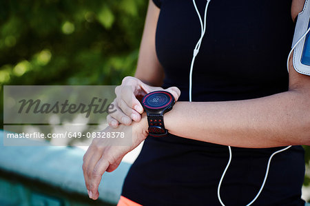 Cropped shot of young female runner setting smartwatch