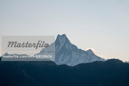 Snow capped mountain peak against dark mountain range, Nepal