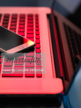 Red light on laptop and mobile phone illustrating danger from hackers
