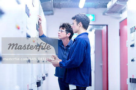 Colleges in control room looking at switchgear