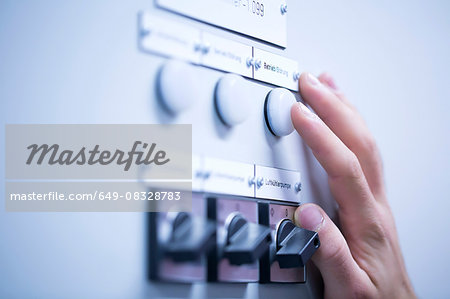 Cropped view of young mans hand adjusting dial on switchgear Cropped view of young mans hand adjusting dial on switchgear