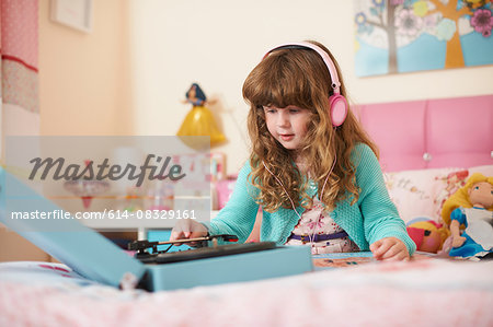 Girl in bedroom wearing headphones and playing vinyl records