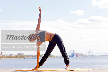 Full length front view of young woman by water in yoga position, Philadelphia, Pennsylvania, USA