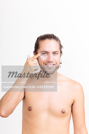 Portrait of young man applying moisturiser