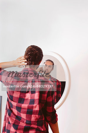 Young man looking in mirror, rear view