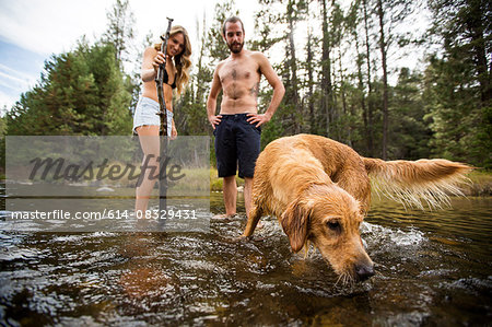 Young couple watching pet dog in river, Lake Tahoe, Nevada, USA