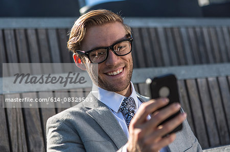 Young businessman reading smartphone text in city