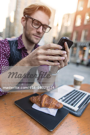 Young businessman having working lunch at sidewalk cafe, New York, USA