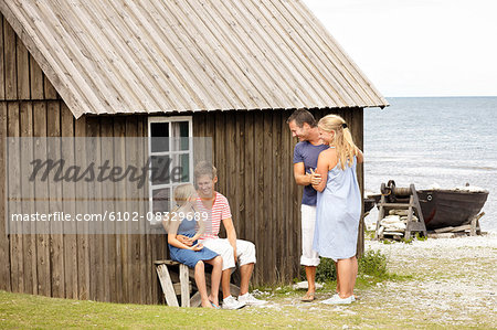 Family near wooden house at sea