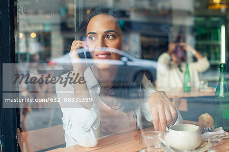 Woman talking on cell phone in coffee shop