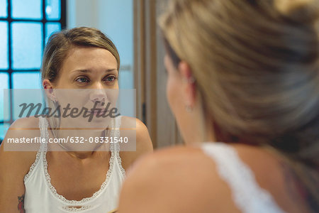 Woman looking at self in bathroom mirror