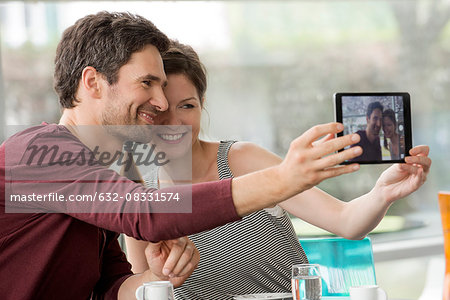 Couple smiling for selfie taken with digital tablet