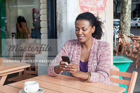 Woman using cell phone at sidewalk cafe
