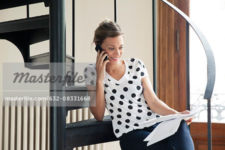 Woman reviewing document while talking on phone