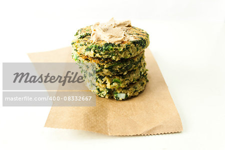 A stack of quinoa, spinach and feta patties topped with Tahini sauce.