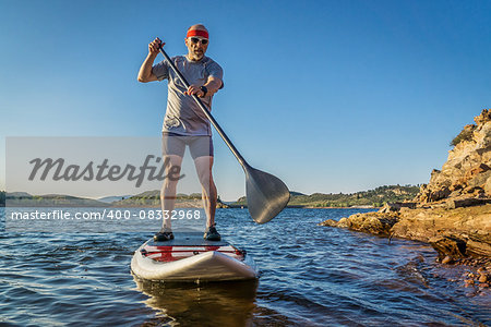 senior male paddler enjoying stand up paddling on a sunny summer day - Horsetooth Reservoir, Fort Collins, Colorado