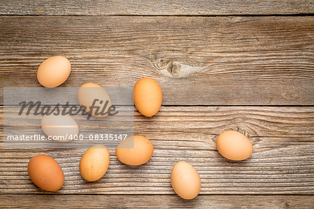 brown chicken eggs on a rustic weathered wooden table, top view with a copy space