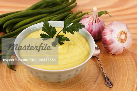 Vegetable cream soup of green beans with parsley  and garlic on wooden table. Selective focus