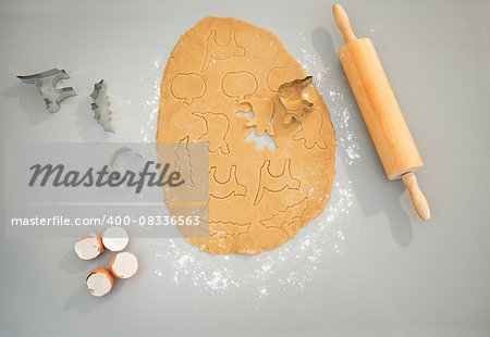 Closeup on shapes of cut out Halloween biscuits in rolled pastry on table in kitchen. Traditional autumn holiday. Upper view