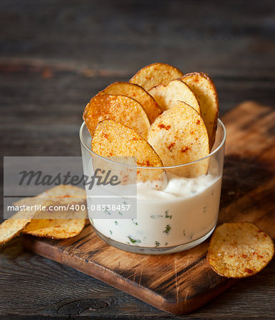 Fried potato chips with spicy sauce served in glass.