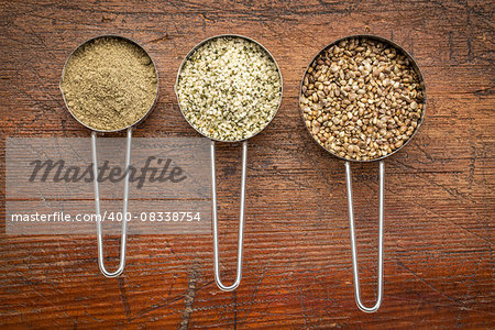 hemp seeds, hearts and protein powder in metal measuring scoops against grunge wood