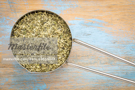 sea lettuce flakes in a metal measuring scoop  against grunge wood