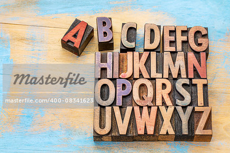 alphabet concept in vintage letterpress wood type stained by color inks against painted wood with a copy space