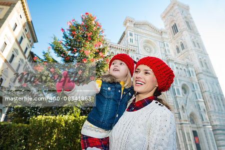 Excited mother and daughter pointing on something while standing near Christmas tree and Duomo in Florence, Italy. Modern family enjoying carousel of Christmas time events in heart of the Renaissance.