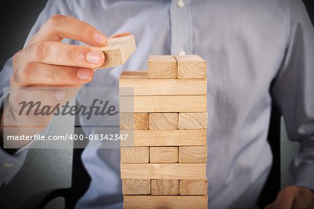 Businessman playing at a wood brick building